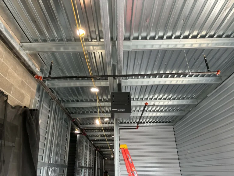 Overhead piping runs and a hung HVAC unit along a building corridor