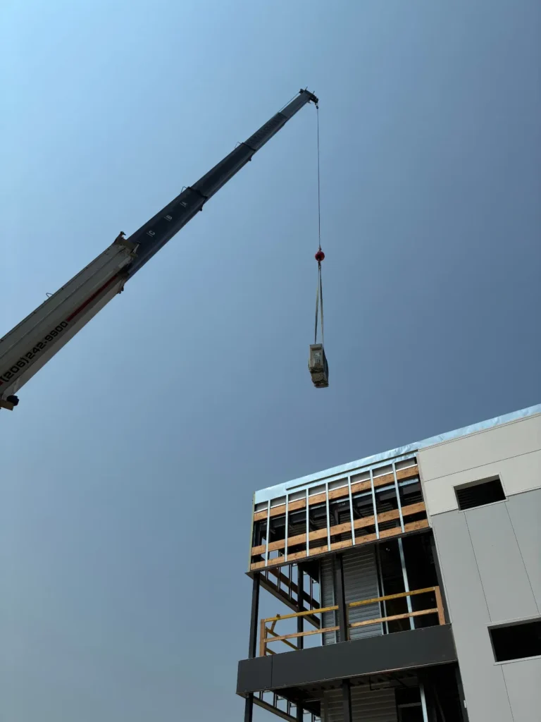 Crane lifting new rooftop HVAC equipment onto a three-story building in Snohomish