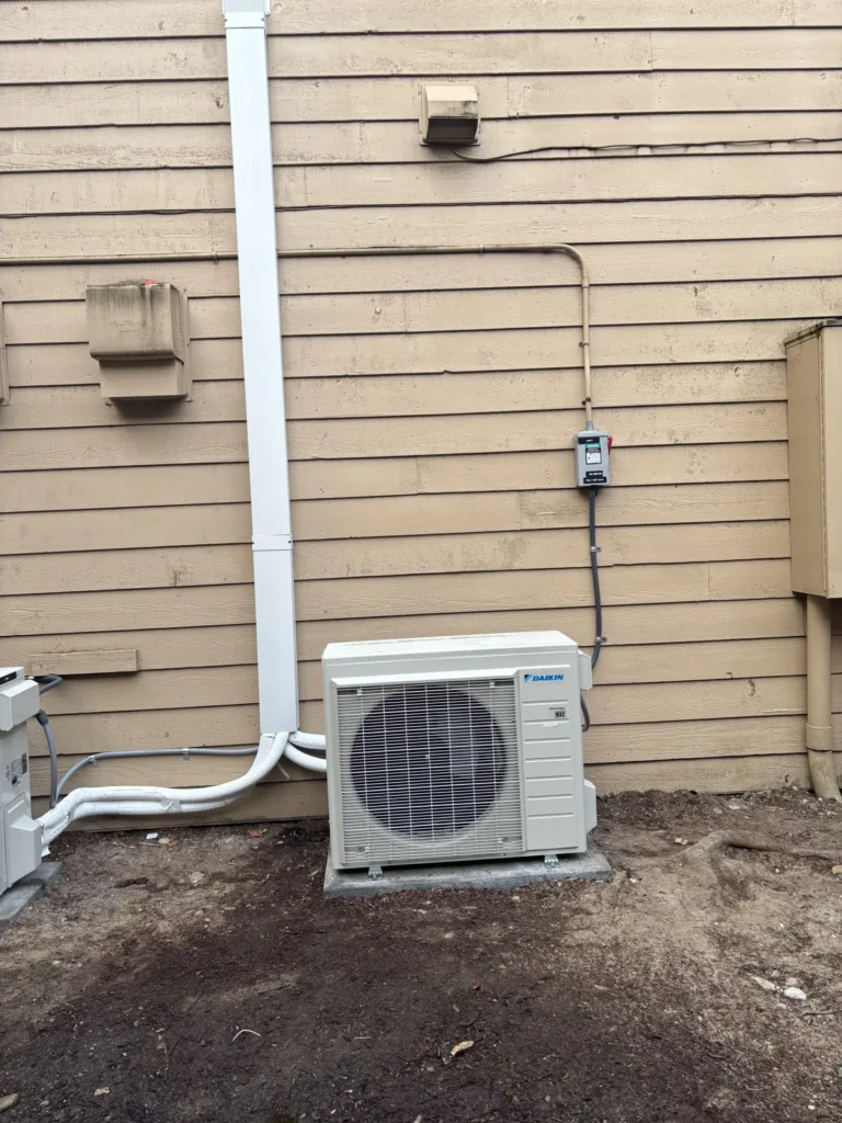 Heat pump condenser with line-set cover running up the siding in Bellevue