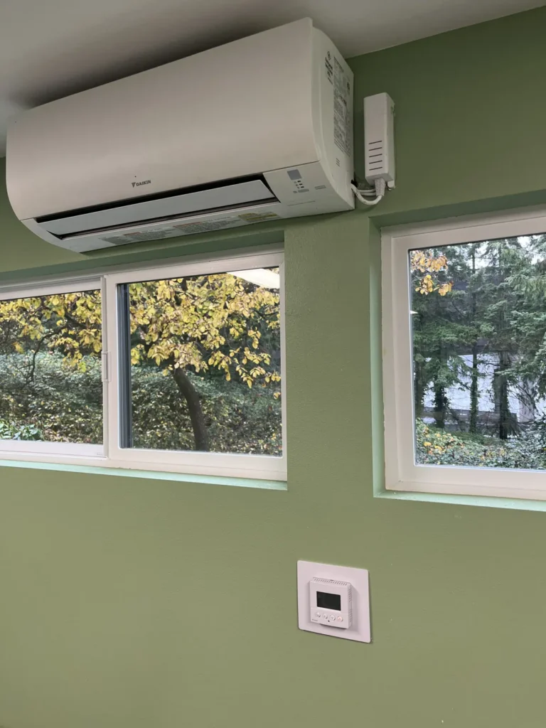 Ductless wall unit above office windows with a wall thermostat