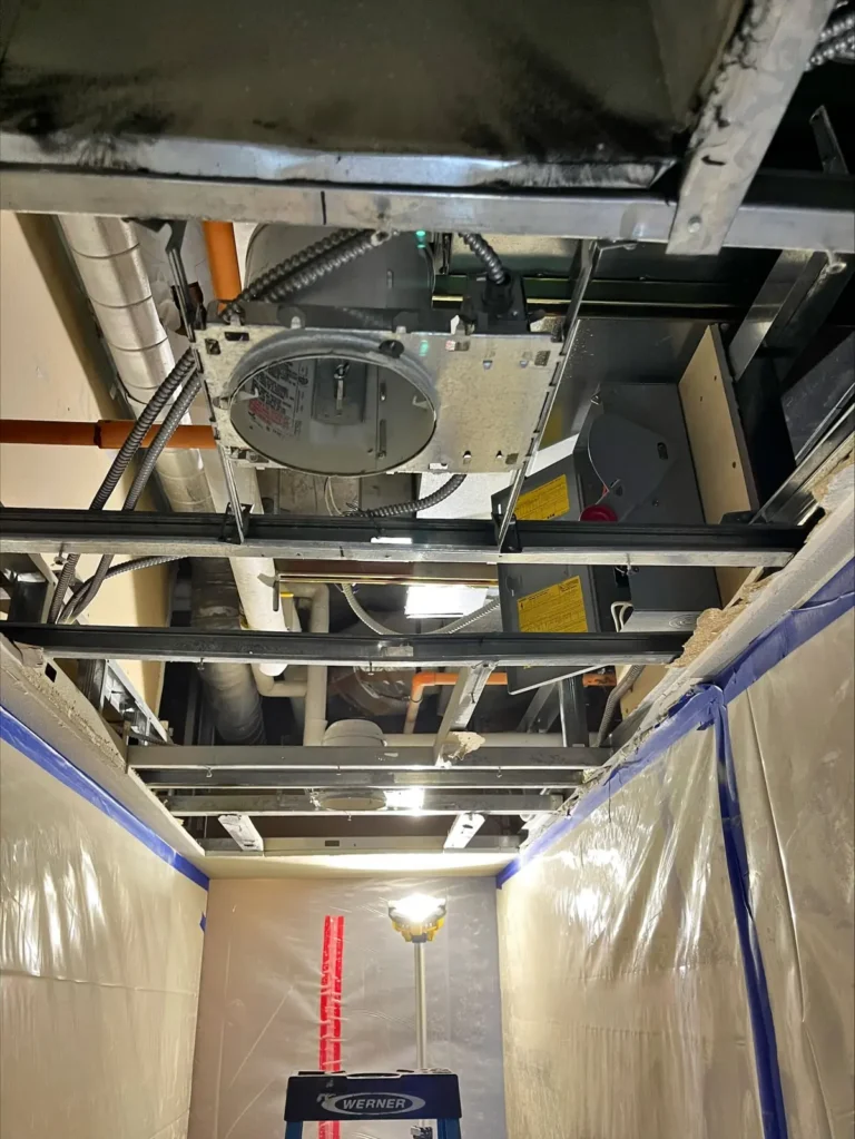 Fan coil unit installed in an open ceiling with the work area taped off