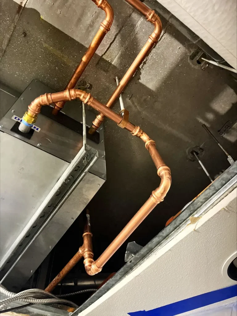 New copper hydronic piping connected to a ceiling fan coil unit