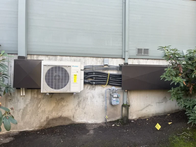 Heat pump condenser with line-set covers along an exterior wall