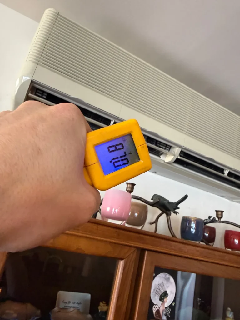 Technician checking supply air temperature at a ductless indoor unit