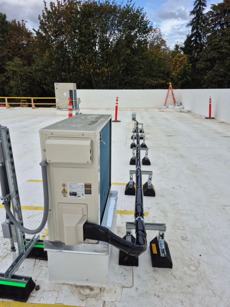 Rooftop heat pump condensing unit with insulated refrigerant lines on roof pipe supports